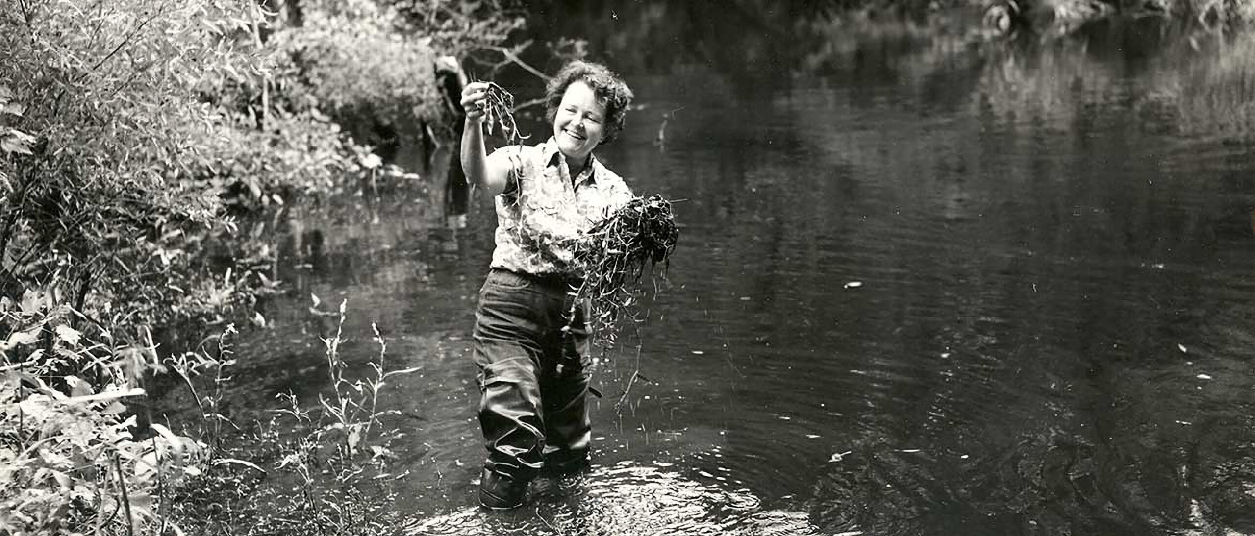 dr_ruth_patrick-Enhanced Black and white photo of Dr. Ruth Patrick wearing waders and standing in a lake.