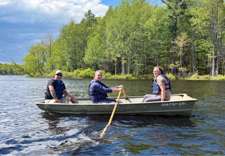 3 people in a row boat on Lake Lacawac
